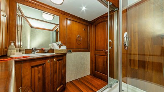 Elegant bathroom with wood panelling, large mirror and modern shower.